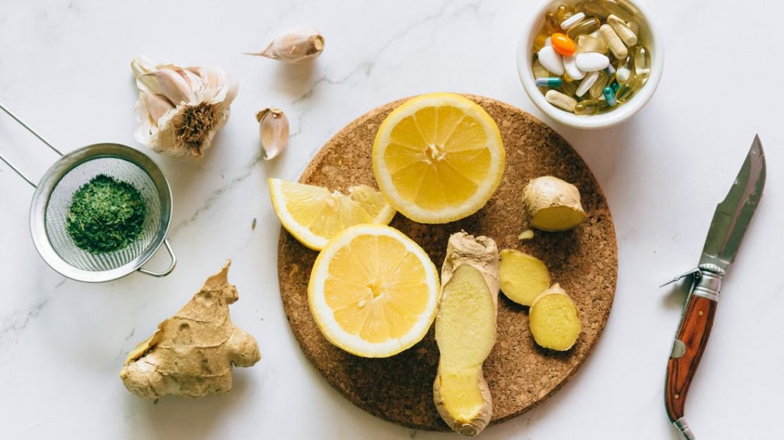 Flat lay of natural remedies including lemon, ginger, and garlic alongside pills.